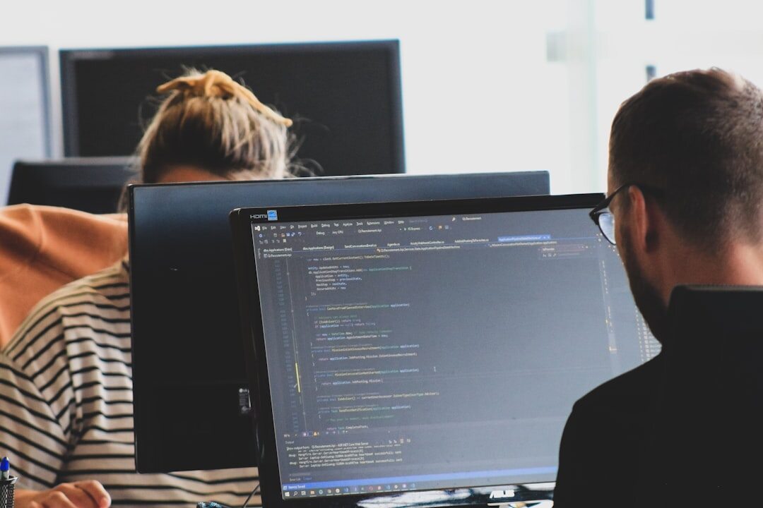 Software developer coding with multiple monitors displaying code